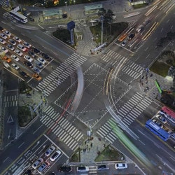 Cruzamento urbano movimentado à noite com ônibus e veículos