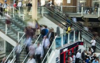 Pedestres circulando em escadas e passarelas de uma estação movimentada