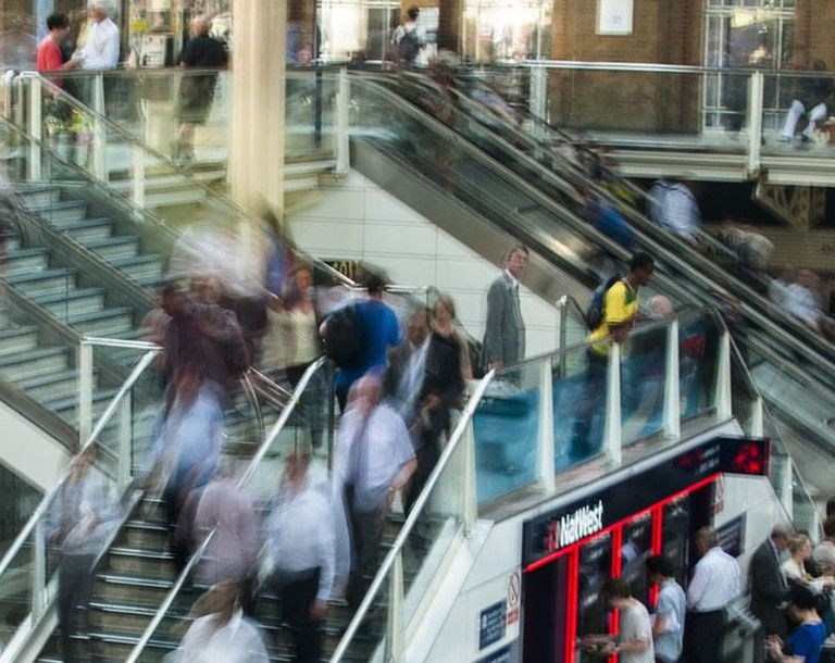 Pedestres circulando em escadas e passarelas de uma estação movimentada