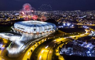 Vista aérea noturna da Arena MRV iluminada com fogos e público no entorno