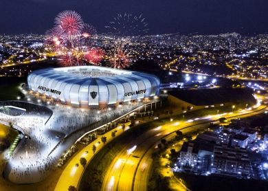 Vista aérea noturna da Arena MRV iluminada com fogos e público no entorno